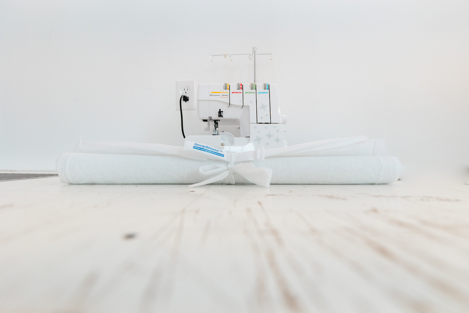 a white roll of breathable fabric sits in front of a white sewing machine with a white wall in the background