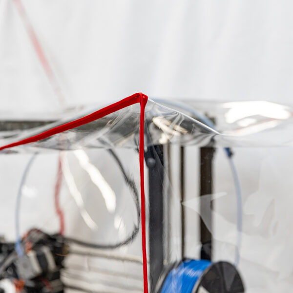 close up of the red fabric trim of a clear dust cover over a 3D printer